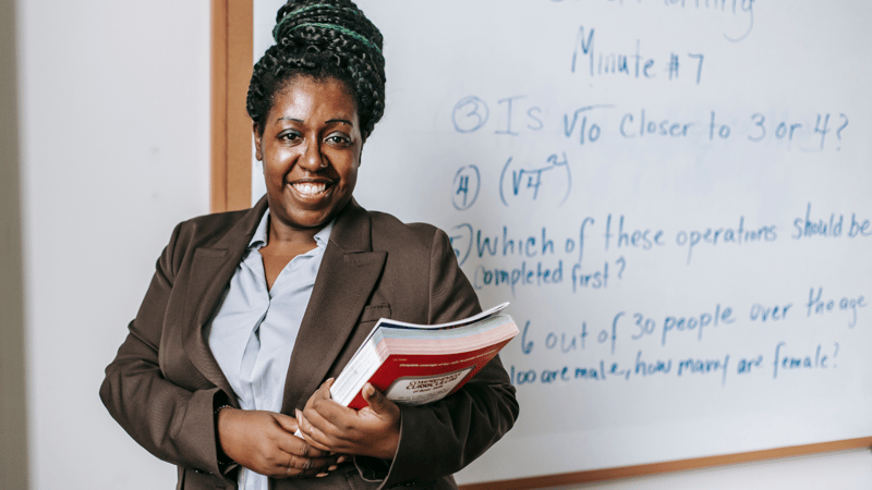 Educator leading a classroom session with clear learning objectives and student-centered strategies written on the board.