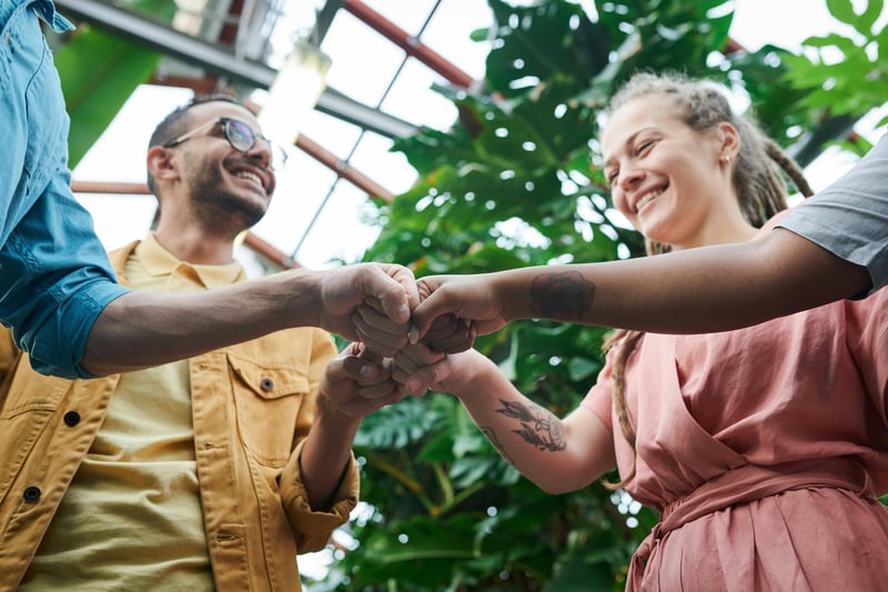 A team of four teachers doing a fist bump with smiles on their faces.