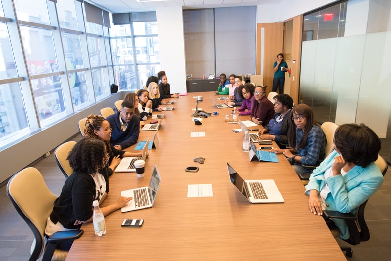Teachers seated around a large conference table engaged in a PD session focused on collaborative goal setting and actionable takeaways.