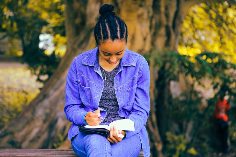 Teacher journaling in a peaceful park to set boundaries and reduce stress during the job hunting process.